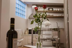 eine Vase mit einer Rose auf einem Tisch mit einer Flasche Wein in der Unterkunft Country Chic in Ioannina city center in Ioannina
