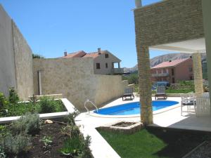 a backyard with a swimming pool and a stone wall at House Sunny Rock Baška in Jurandvor