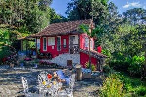 a red house with a table and chairs at Pousada Refúgio das Aves in Visconde De Maua