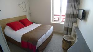 a bedroom with a bed with red pillows and a window at Hôtel Ar Iniz in Saint Malo