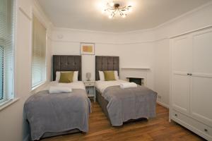 a bedroom with two beds and a chandelier at Victoria’s Place in Chelmsford