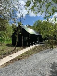 um celeiro preto com um telhado verde ao lado de uma estrada em Alder Cabin em Kilkenny