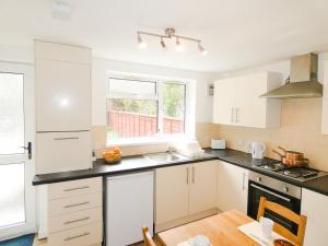 uma cozinha com armários brancos e bancadas pretas em 3 Bedroom House for Brecons and Bike Park Wales em Merthyr Tydfil