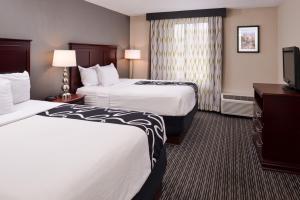 a hotel room with two beds and a flat screen tv at La Quinta by Wyndham Indianapolis South in Indianapolis