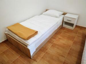 a small bed with white sheets and a yellow blanket on it at DCK Apartments in Kostrena