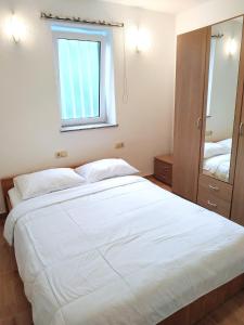 - une chambre avec un grand lit blanc et une fenêtre dans l'établissement DCK Apartments, à Kostrena