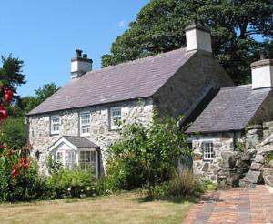 an old stone house with a slate roof at Coed y Berclas cottage, private orchard with stunning views in Llandegfan