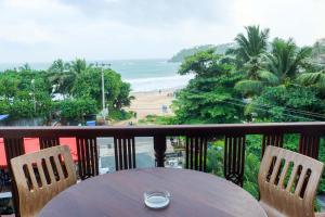 einen Tisch und Stühle auf einem Balkon mit Blick auf den Strand in der Unterkunft Randiya Sea View Hotel in Mirissa