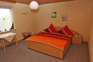 ein Schlafzimmer mit einem großen Bett mit roten Kissen in der Unterkunft Ferienwohnung Sauer in Hillscheid