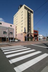 uma faixa de pedestres numa rua da cidade com um grande edifício em Hotel Promote Hakodate em Hakodate