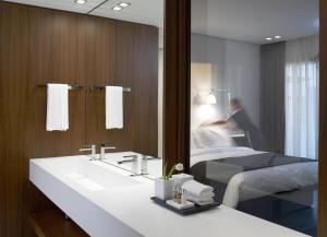 a bathroom with a sink and a bed and a mirror at The Met Hotel Thessaloniki, a Member of Design Hotels in Thessaloniki