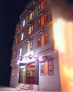 a tall white building with lit up windows at night at Hotel King in Haridwār