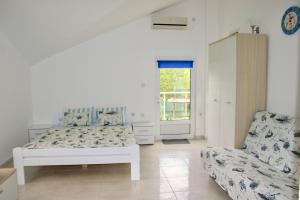 a white bedroom with a bed and a chair at Studio apartments Morinj in Donji Morinj