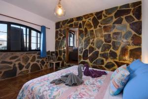 - une chambre avec un mur en pierre et un lit dans l'établissement Buda, à Tinajo