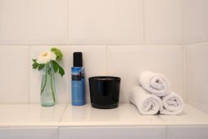 eine Badezimmertheke mit Handtüchern und einer Vase aus Blumen in der Unterkunft Bed and Breakfast Het Dijkhuis Eersel in Eersel