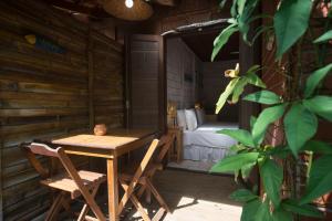a wooden table and chairs on a porch with a bed at Pousada Treze Luas in Ilha do Mel