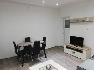 a living room with a table and chairs and a television at Rooms Jelena in Zrenjanin