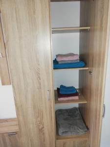 Un armario de madera con algunas toallas plegadas. en Rooms Jelena, en Zrenjanin