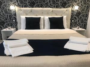 ein großes weißes Bett mit schwarzen und weißen Kissen in der Unterkunft Alba rooms in La Spezia