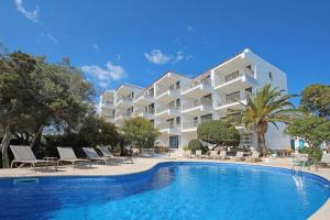 a hotel with a swimming pool in front of a building at Aparthotel Niu d´Aus in Portopetro