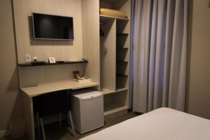 um quarto com uma secretária e uma televisão na parede em Scarpelli Palace Hotel em Sorocaba