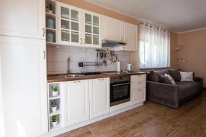 una cocina con armarios blancos y un sofá en una habitación en Apartmani Slavek, en Jastrebarsko