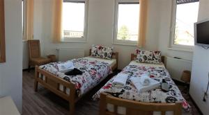 two beds in a small room with two windows at Apartments&Rooms Mido in Visoko