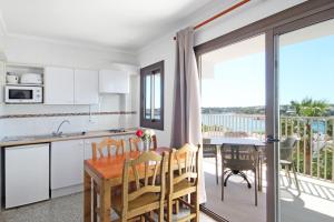 a kitchen and dining room with a table and a balcony at Aparthotel Niu d´Aus in Portopetro