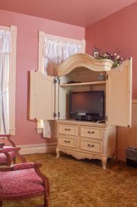 um centro de entretenimento com uma televisão num quarto em The Historic Wolf Hotel em Ellinwood