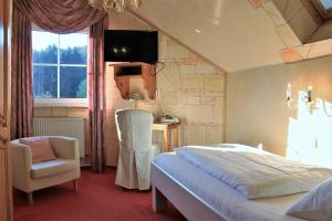 a bedroom with a bed and a chair and a desk at Historisches Landhotel Studentenmuehle in Nomborn