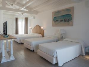 Cette chambre blanche comprend 3 lits et une table. dans l'établissement Park Hotel Asinara, à Stintino