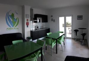 uma cozinha e sala de estar com mesas e cadeiras verdes em Arrifana Guest House em Aljezur