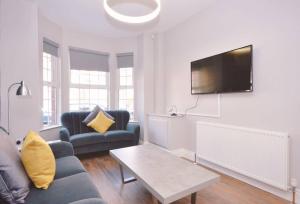 a living room with a couch and a tv on a wall at Queens Quarter Townhouse 2 in Belfast