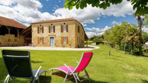 two chairs sitting in the grass in front of a house at Le Guitou in Monlezun