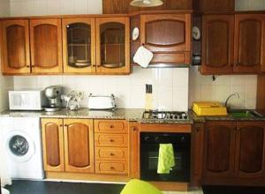 uma cozinha com armários de madeira e um forno com placa de fogão em Praia da Torreira à Vista em Torreira