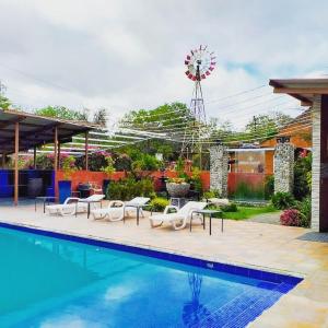 a pool with chairs and a windmill in a yard at Windmill Hostal in Valle de Anton