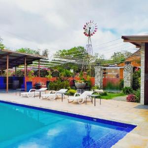 una piscina con sillas y un molino de viento en un patio en Windmill Hostal, en El Valle de Antón