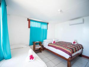 a bedroom with two beds and a blue window at Magnific Rock - Surf Resort & Yoga Retreat Nicaragua in Popoyo