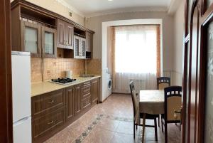 a kitchen with wooden cabinets and a table and a window at Truskavets Lux Apartment in Truskavets