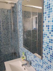y baño con lavabo, espejo y azulejos azules. en Sossego Da Ria, en Praia da Barra