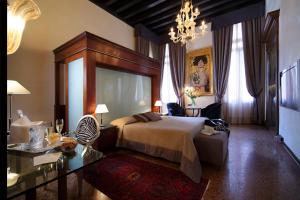 una camera con letto, tavolo e lampadario a braccio di Hotel Liassidi Palace a Venezia