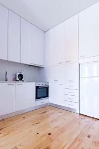 an empty kitchen with white cabinets and a wooden floor at Bom Porto Apartments in Porto