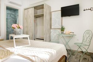 a bedroom with a bed and two chairs and a tv at Meltemi luxury apartments in Nea Roda