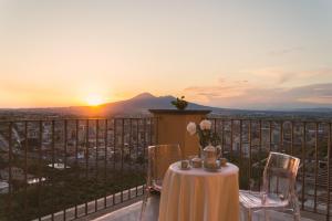 een tafel en stoelen op een balkon met uitzicht op de zonsondergang bij Villa Di Natale in Pagani