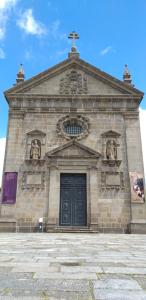 a large stone church with a black door and a cross at SÃO VICTOR Studios HISTORIC CENTER in Braga