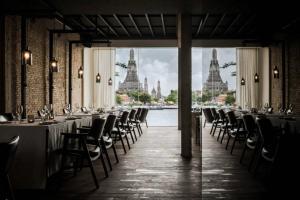 a dining room with tables and chairs and a view of the city at Sala Rattanakosin Bangkok in Bangkok