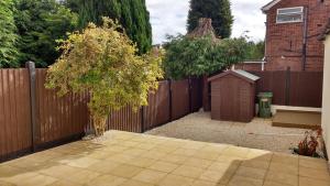 a backyard with a wooden fence and a small tree at East Park House in Wolverhampton