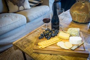 a table with cheese and grapes and a glass of wine at Camellia Cottage in Cessnock