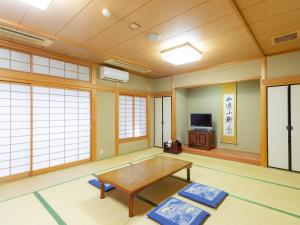 a living room with a table and a tv at Miyama Nature and Culture Village Kajikaso in Nakamura