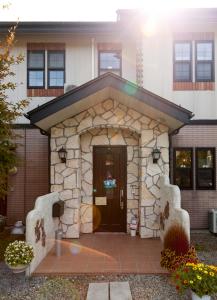 un pequeño edificio con una puerta delante de una casa en ペンションカパルア軽井沢, en Karuizawa